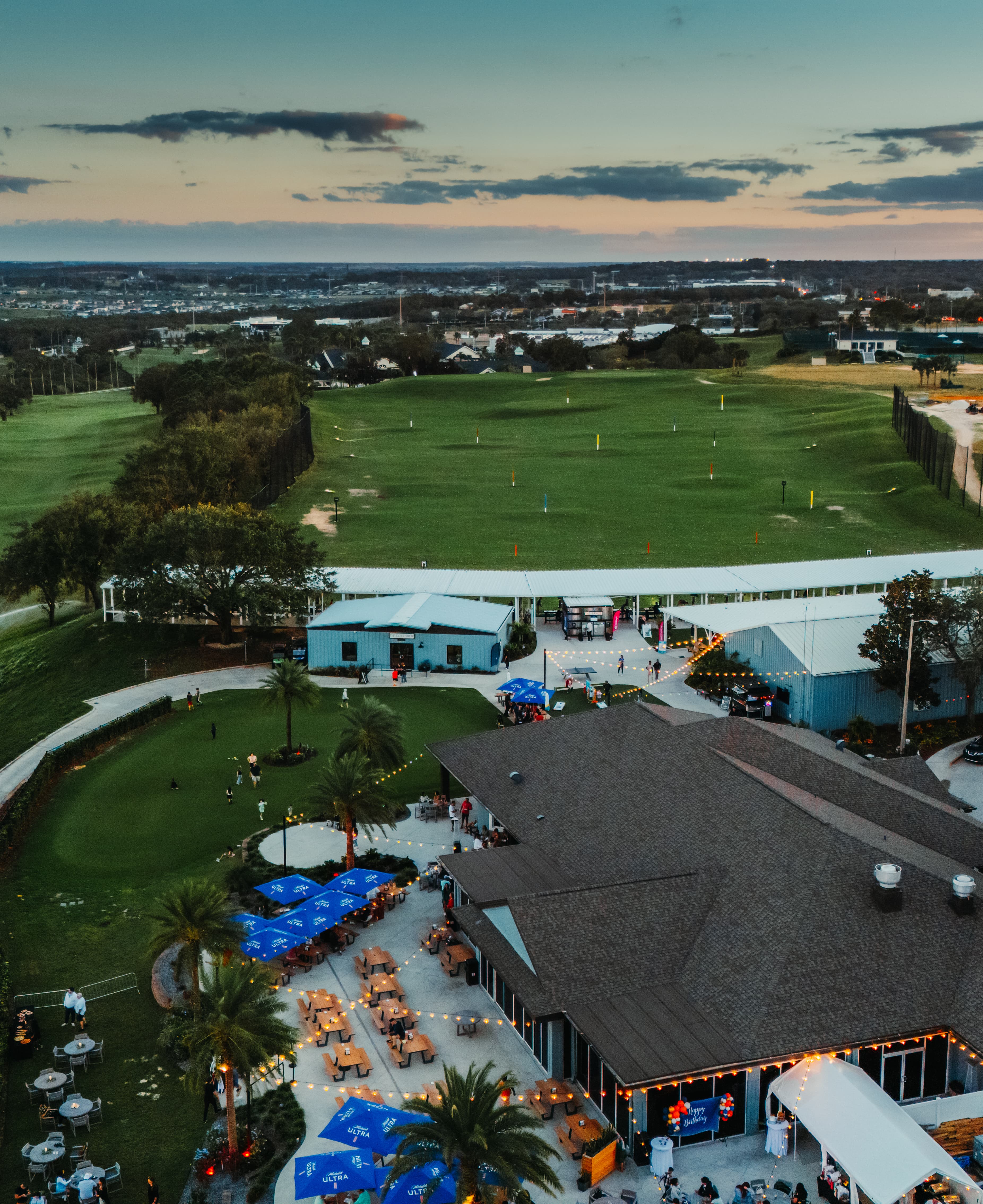 Aerial overview of the range facility and clubhouse at sunset